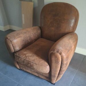 Fauteuil club recouvert de suédine effet vieilli marron sur 4 pieds en bois noir. 80 x 82 x 87 cm. Localisation : 30 rue Beauregard - 60440 Nanteuil-le-Haudouin