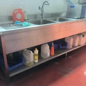 Plonge adossée en inox alimentaire, avec 2 bacs de lavage, 1 bac avec couvercle et 1 étagère basse. Dimensions : 100 x 290 x 80 cm.