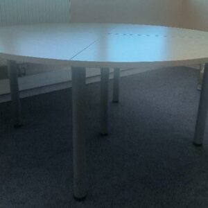 Table ronde, plateau en bois composé de 4 éléments triangulaires, reposant sur 5 pieds droits en métal de couleur gris réglable en hauteur. Dimensions : 74 x 160 cm. (2ème étage - salle de stockage des périmés)