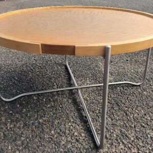 Table basse design Hans J. Wegner modèle CH417 édition CARL HANSEN & SØN, plateau rond amovible en bois de couleur hêtre et piètement pliant en acier inoxydable. Diamètre : 62 cm. Hauteur : 33 cm. Numéro de série 613 836. Localisation : 30 rue Beauregard 60440 Nanteuil-le-Haudouin.