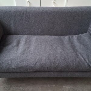 Canapé de marque Prostoria recouvert de feutrine grise, pieds en bois. 67 x 177 x 94 cm.